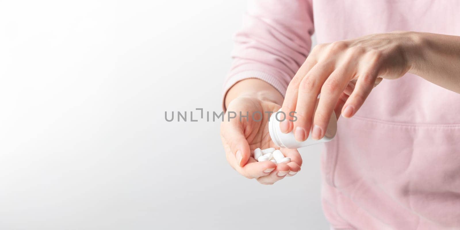 Female taking medicine, holding white pill and a glass of water on white background. Concept of health care, dietary supplements, treatment of depression and diseases. High-quality photo