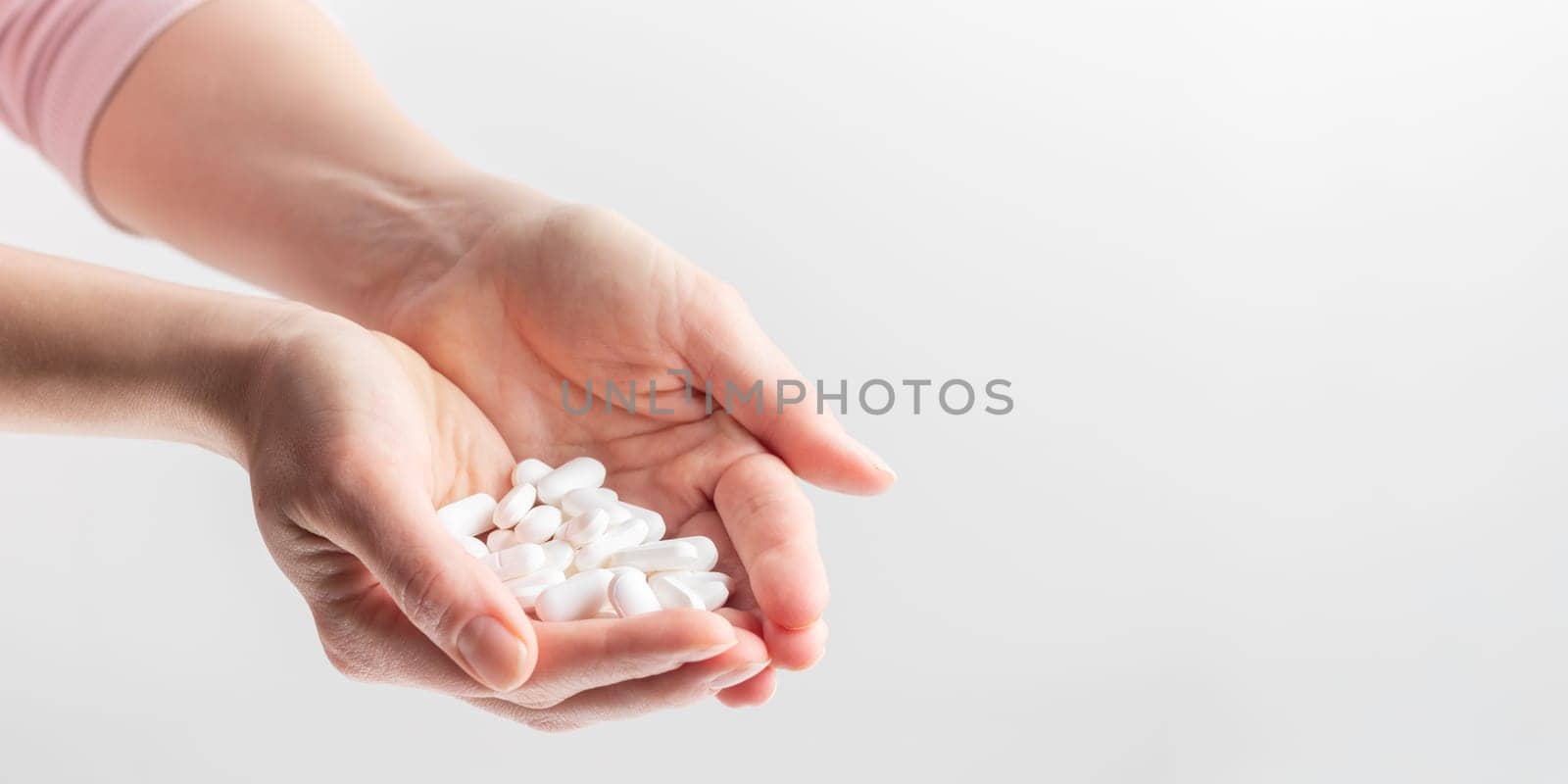 Female taking medicine, holding white pill and a glass of water on white background. Concept of health care, dietary supplements, treatment of depression and diseases. High-quality photo