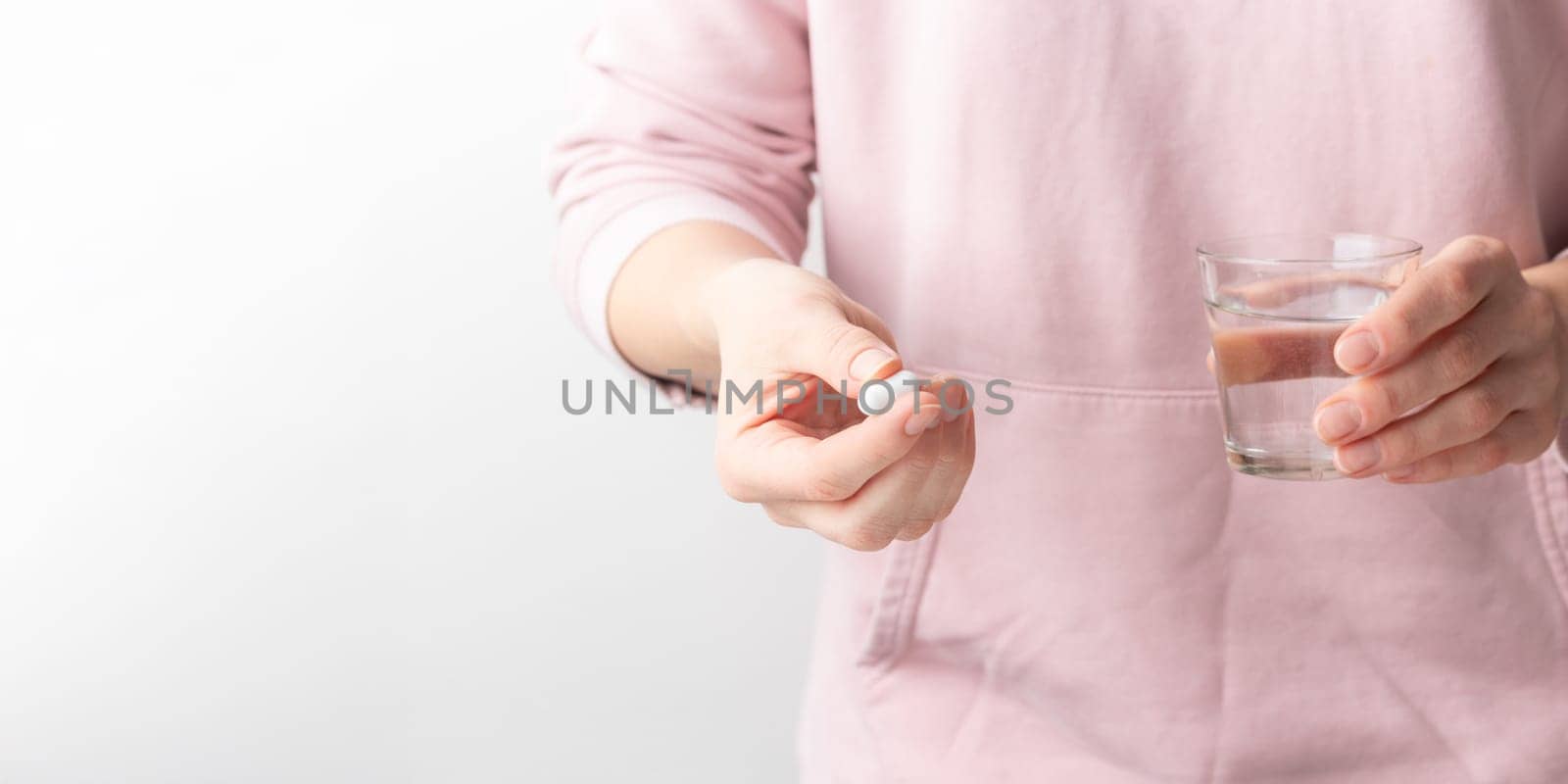 Female taking medicine, holding white pill and a glass of water on white background. Concept of health care, dietary supplements, treatment of depression and diseases. High-quality photo