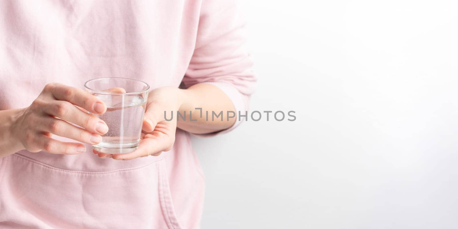 Female hand holding a clear glass of water. A glass of clean mineral water in hands, healthy drink, water balance, concept of environment protection and healthcare, World Water Day