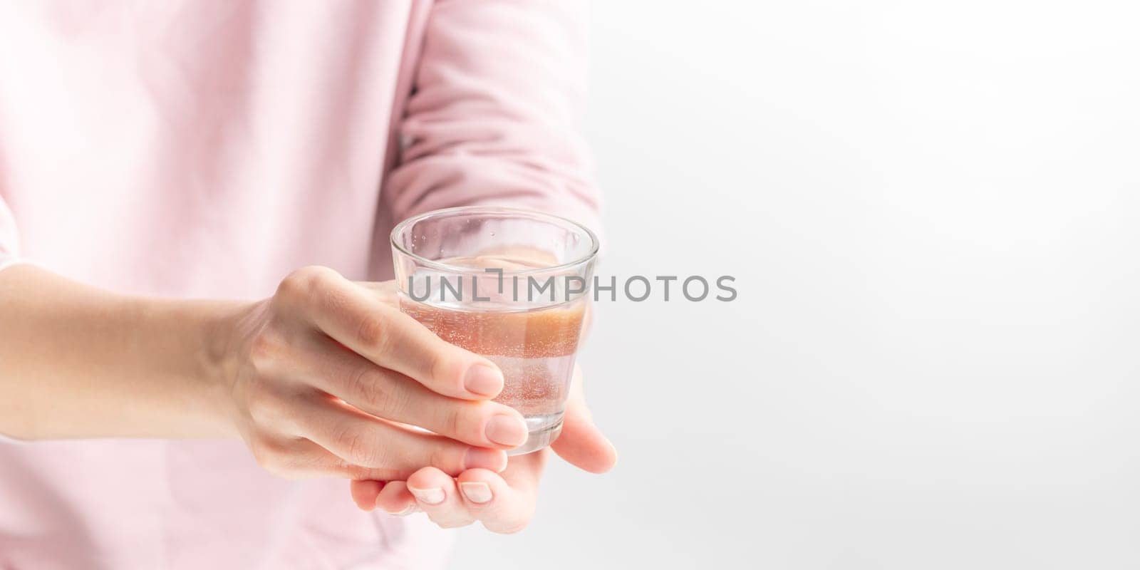 Female hand holding a clear glass of water. A glass of clean mineral water in hands, healthy drink, water balance, concept of environment protection and healthcare, World Water Day
