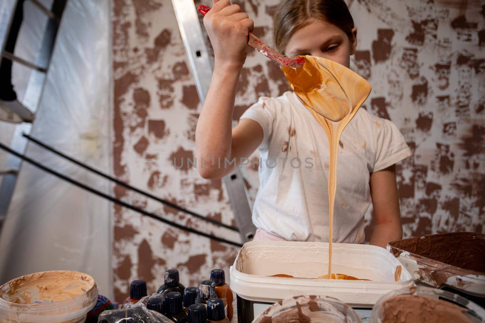 A young girl is happily painting and joyfully showcasing her creativity in a beautiful, rustic setting