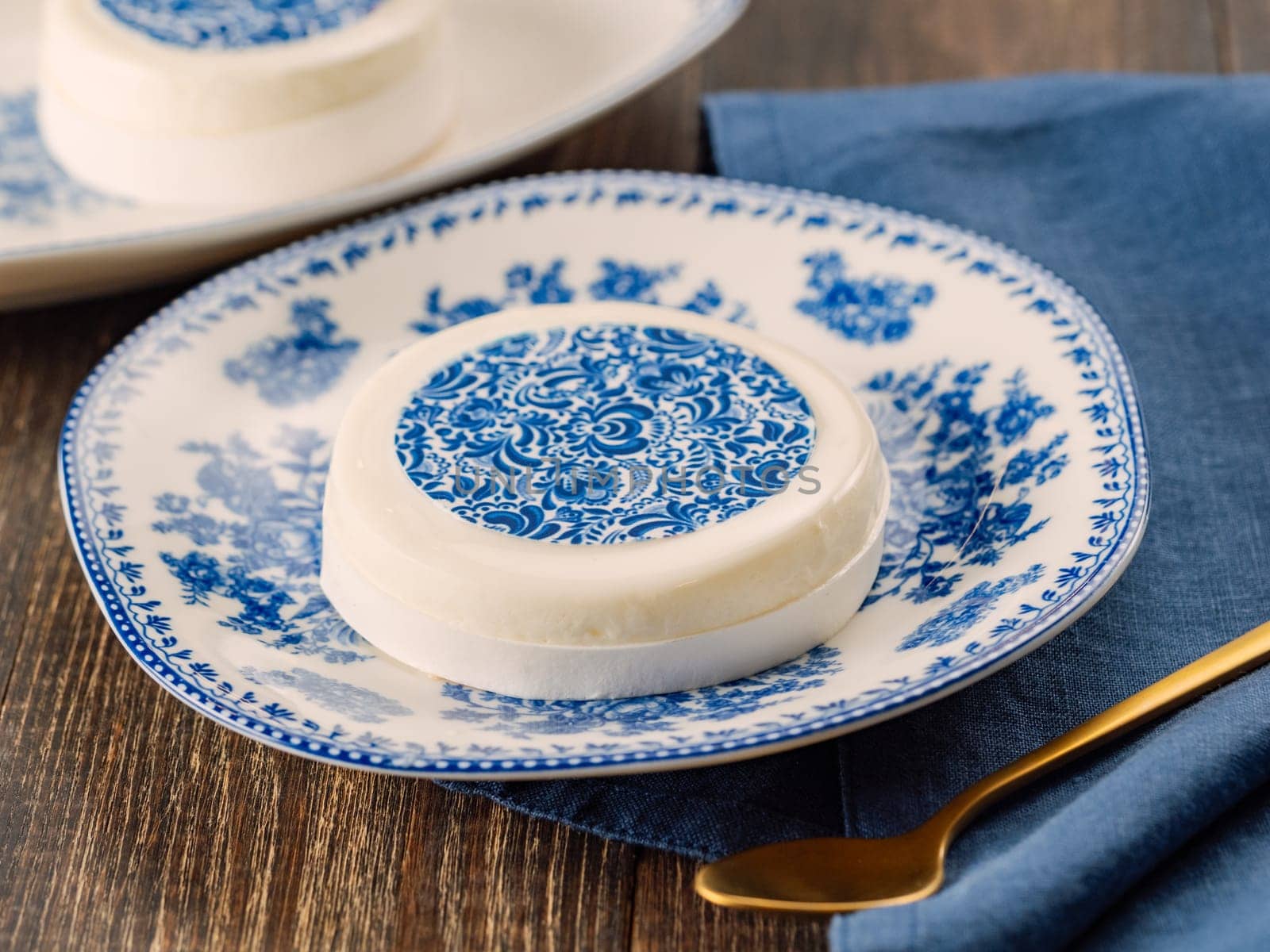 Pastry dessert in Gzhel rustic style. Sweet pastry decorated blue flowers photo printing on sugar paper. Mini cake Gzhel on plate over wooden tabletop background. Closeup