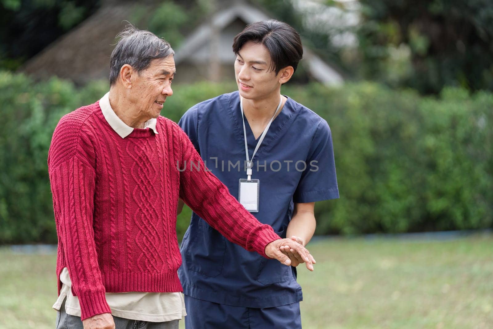 A dedicated young caregiver assists an elderly man, helping him navigate the outdoors while providing comfort and companionship in a peaceful garden.