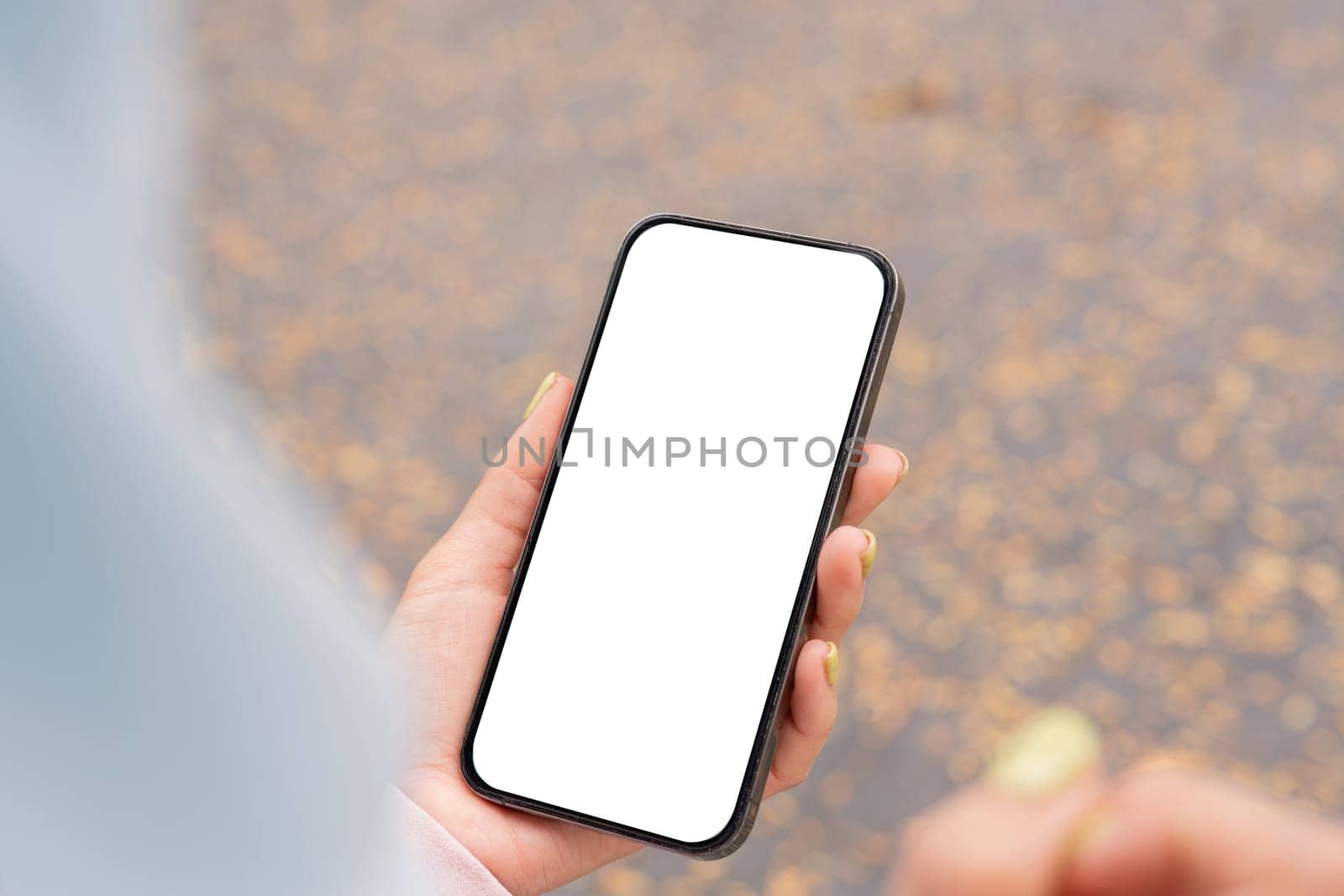A person holds a smartphone with a blank screen capturing a moment in an outdoor urban environment.