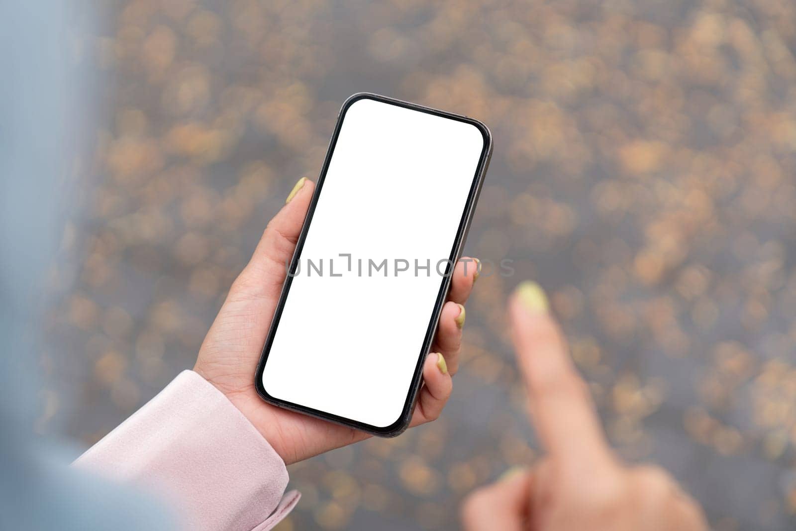 A person points at a blank smartphone screen showcasing digital interaction in an urban outdoor environment.