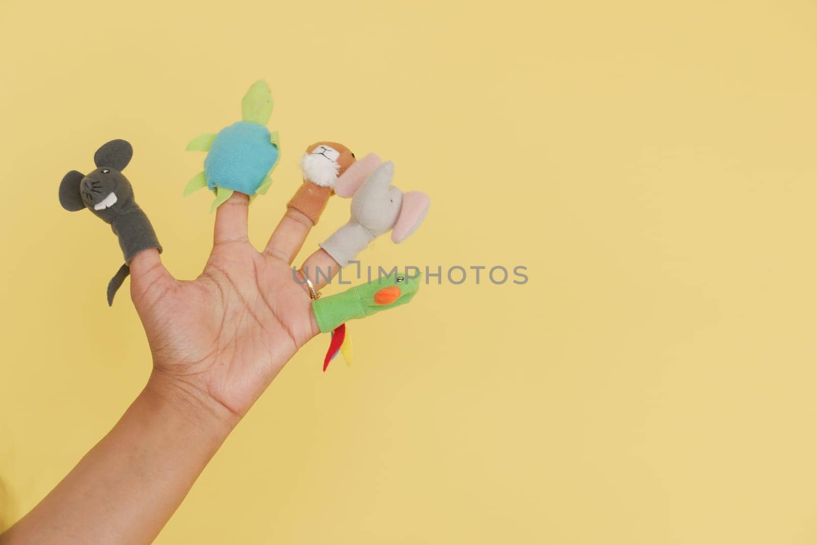 A hand displays colorful finger puppets in a cheerful setting.