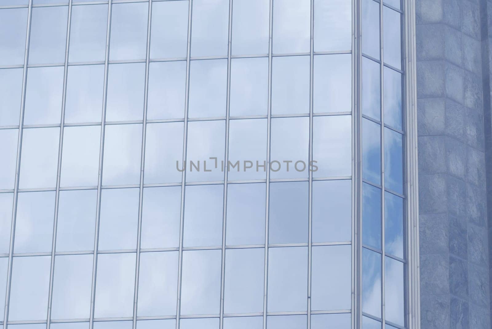 Glass windows reflect clouds in a modern urban environment.