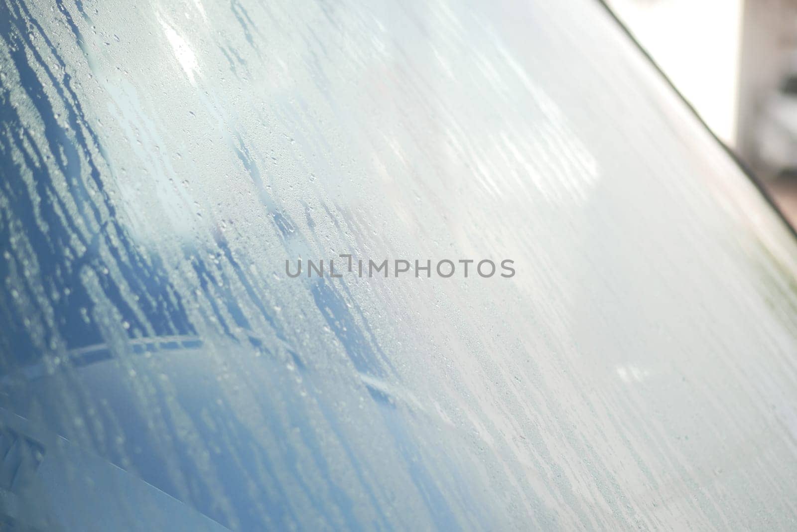 Water droplets cling to a car windshield on a chilly morning.