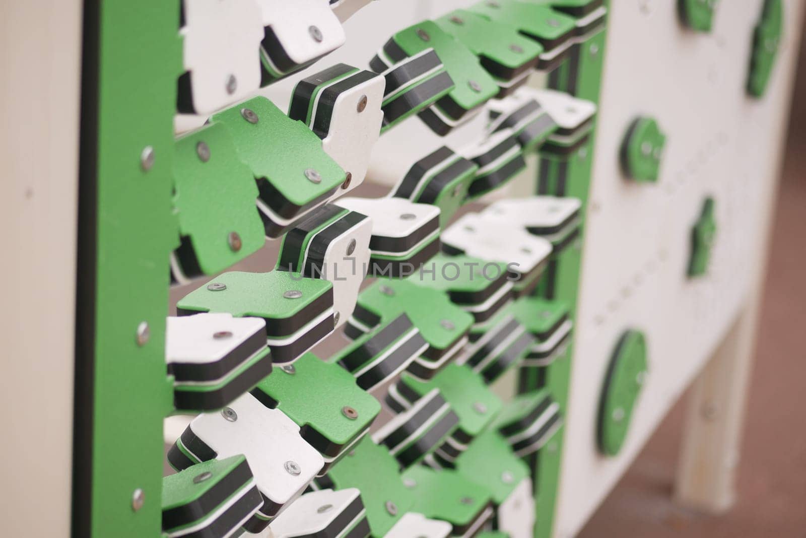 Climbing wall with green and white holds invites climbing enthusiasts.