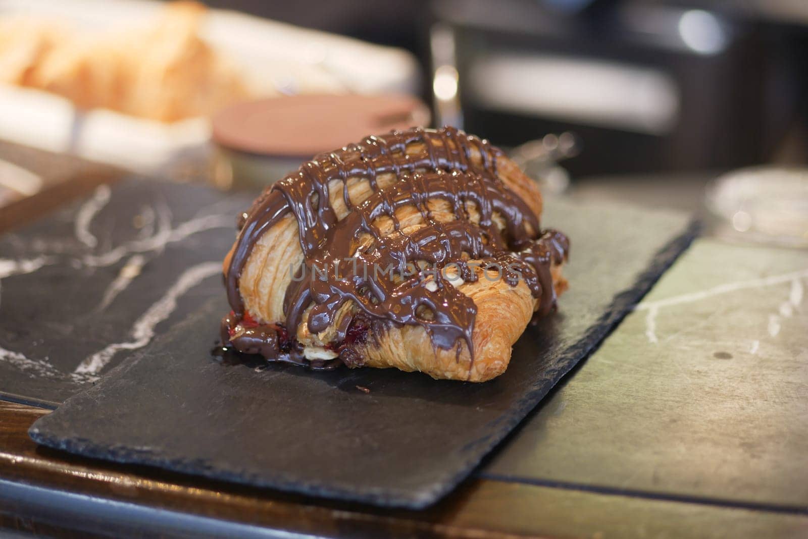 Freshly baked croissant with rich chocolate topping on display at cafe.