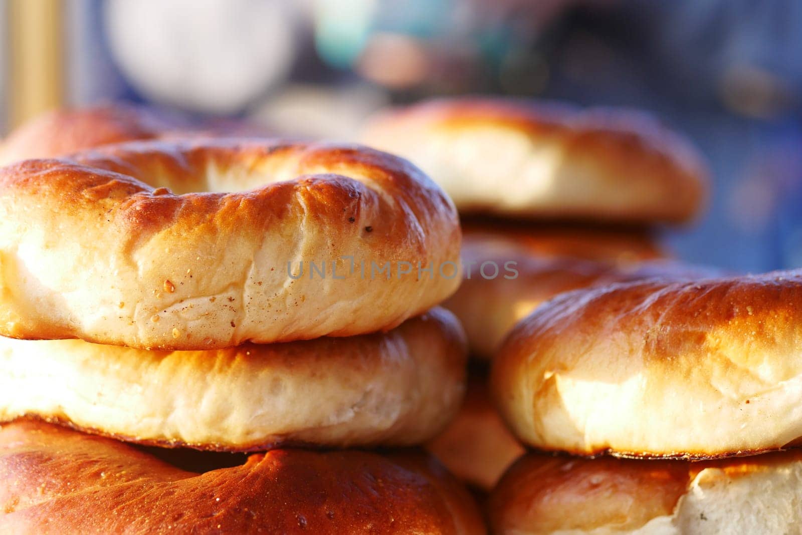 Warm, golden bagels stacked high at a bustling bakery in the morning.