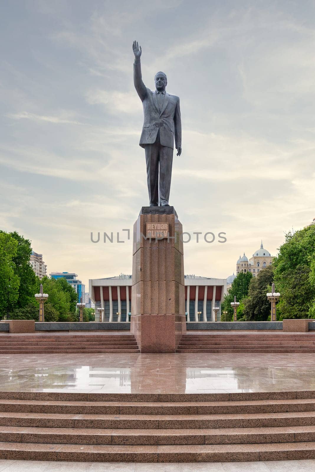 Baku, Azerbaijan - May 5, 2024: Brass statue of Heydar Aliyev, dedicated to the former Azerbaijani President, in Heydar Aliyev Square, in front of a palace that bears the president name
