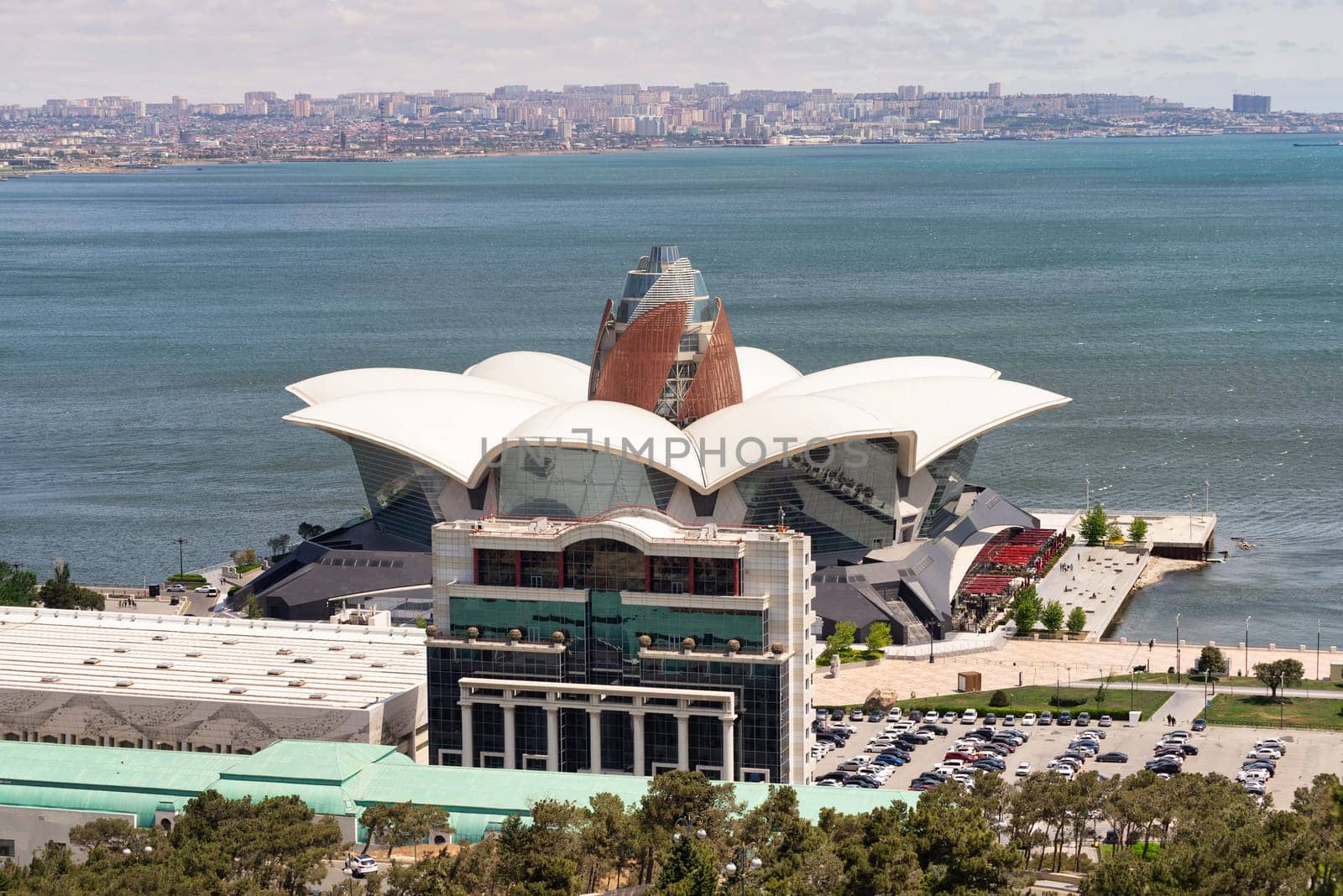 The waterfront view showcases Deniz Mall in the foreground, against a blue sky in Baku, Azerbaijan