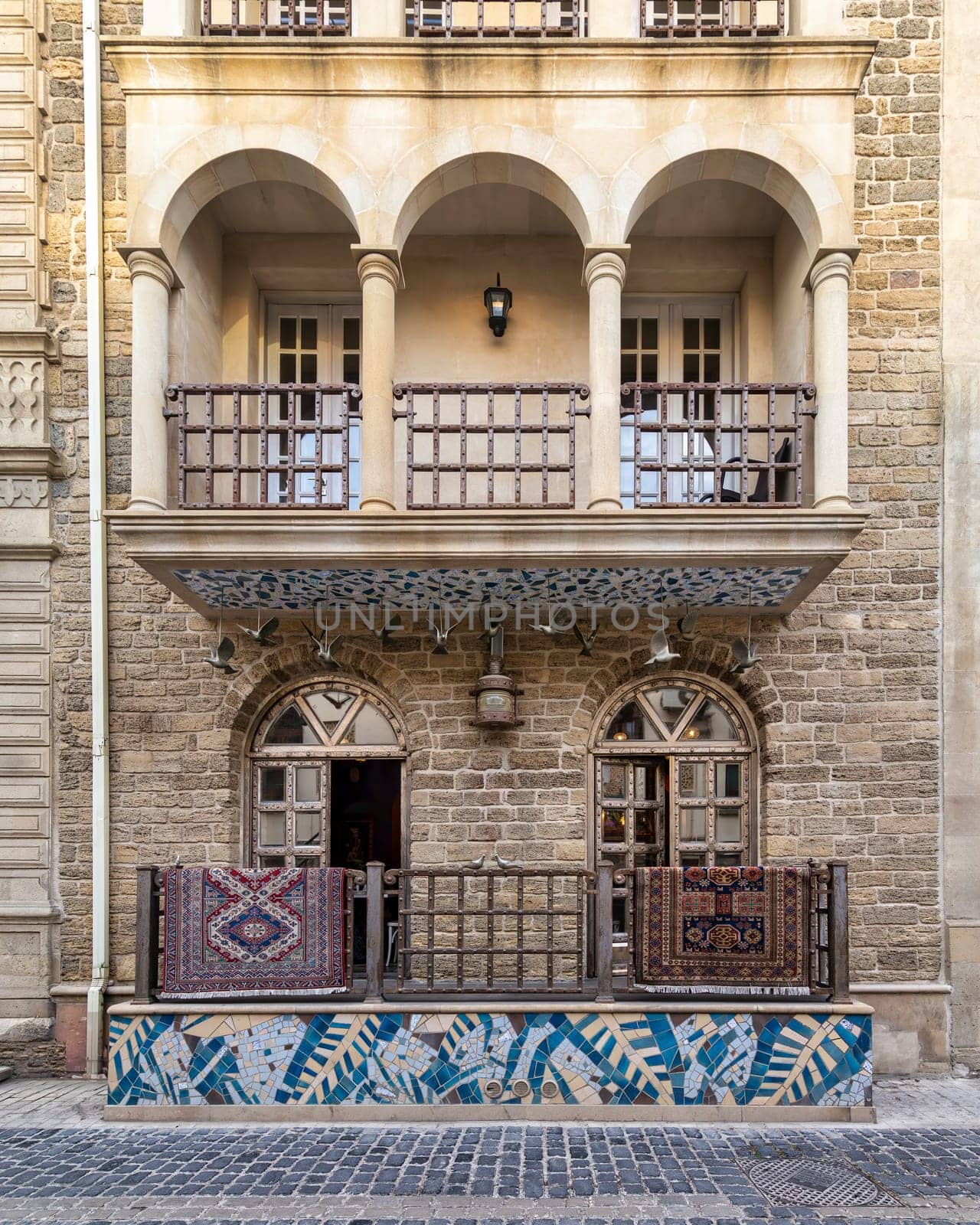 Baku's Icheri Sheher: Cobblestone alleys, stone buildings with arched windows, balconies, and intricate carvings. Vibrant Azerbaijani carpets hang from balconies, adding to its historic charm