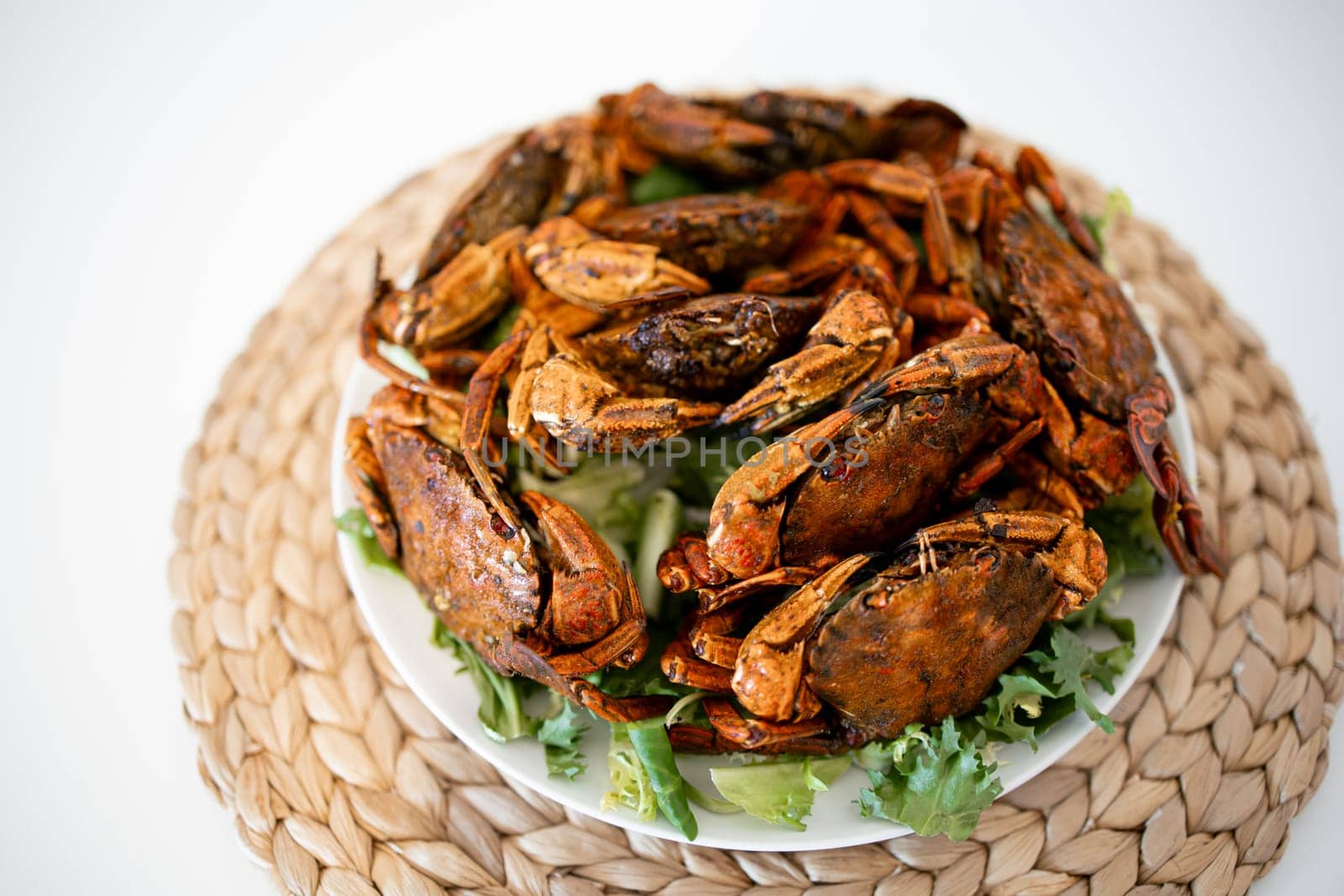 Delicious spicy whole roasted crabs on woven mat background.