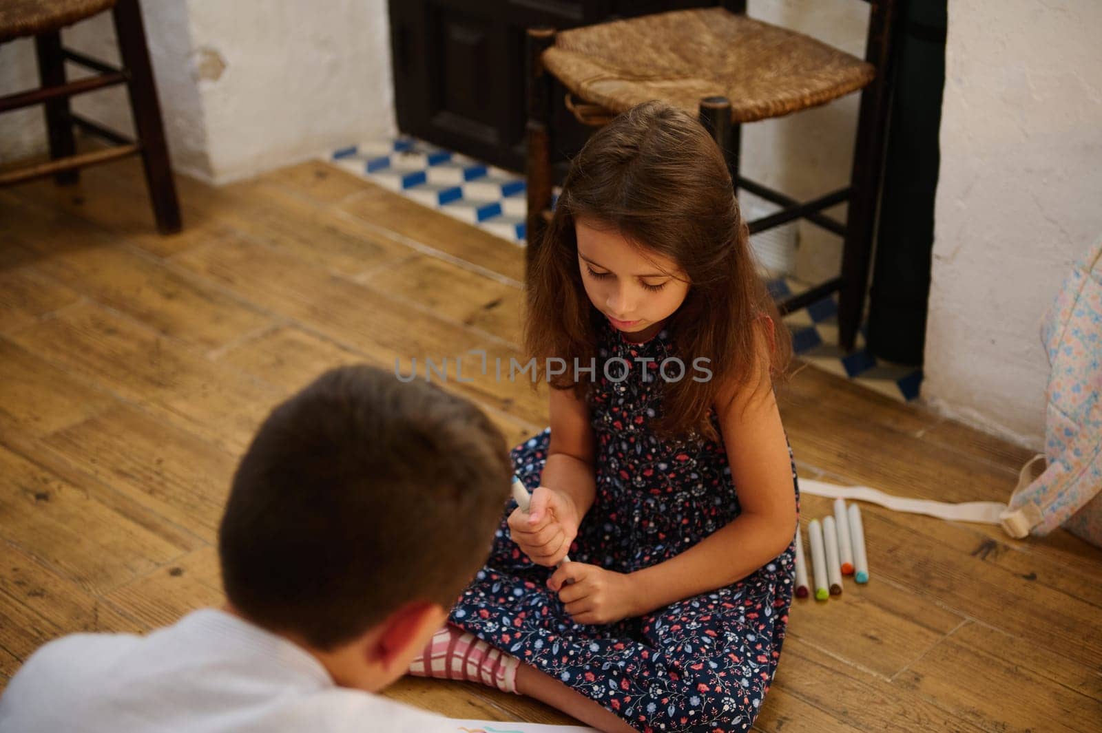 Two children engage in a creative activity, using markers and sketching on paper, fostering imagination.