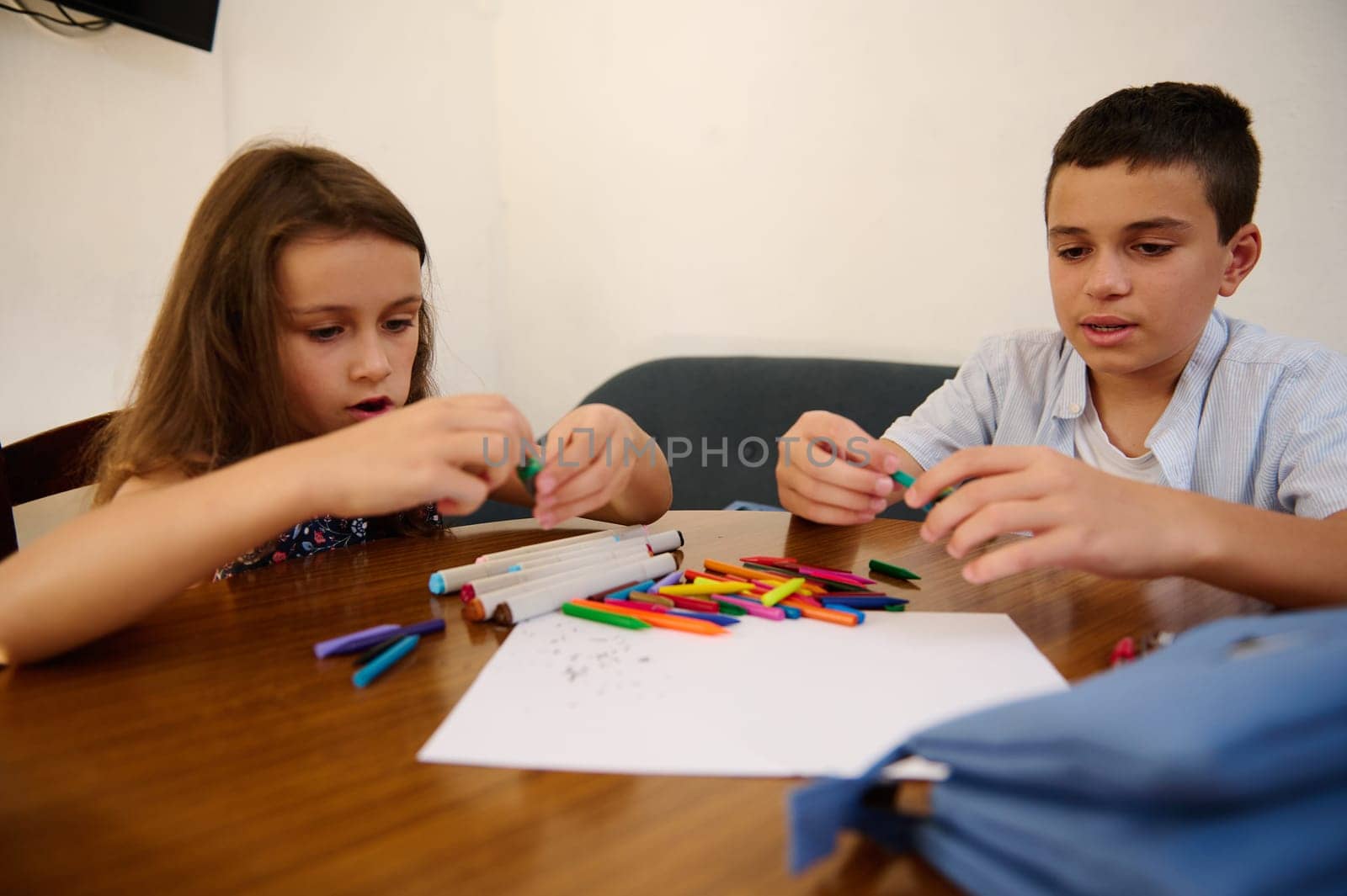 Two children enjoy a creative art activity, focusing on using colorful materials and stationery.
