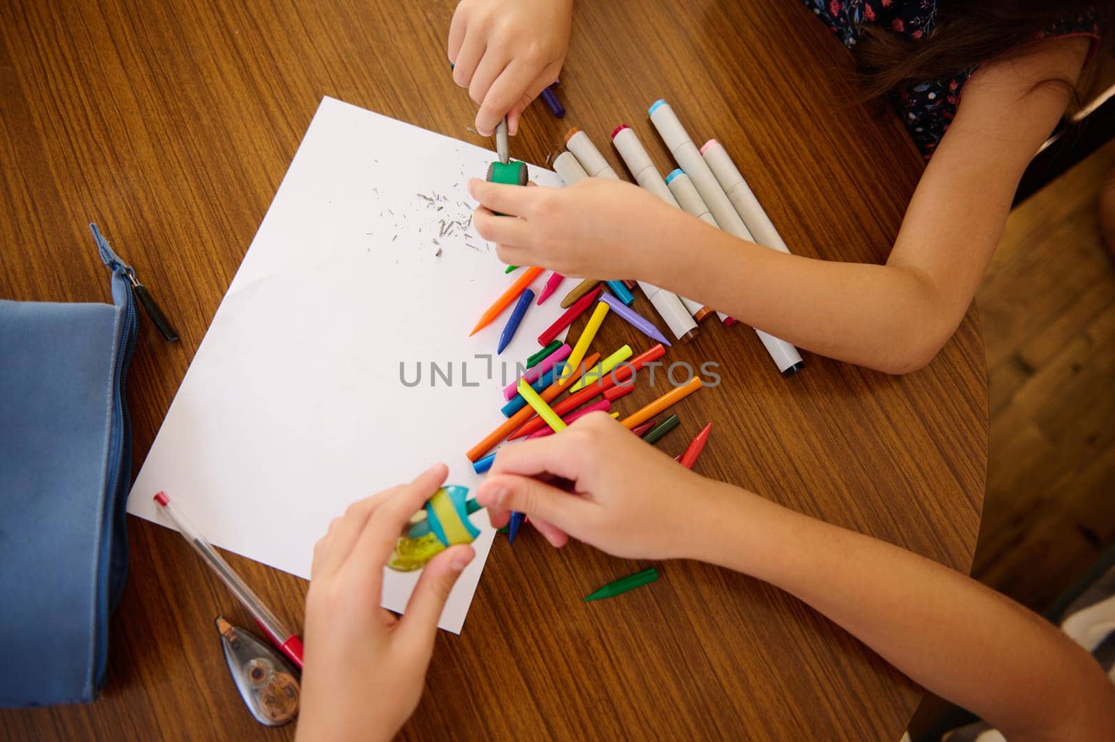 Two children using various colorful supplies for artistic activities, emphasizing creativity.