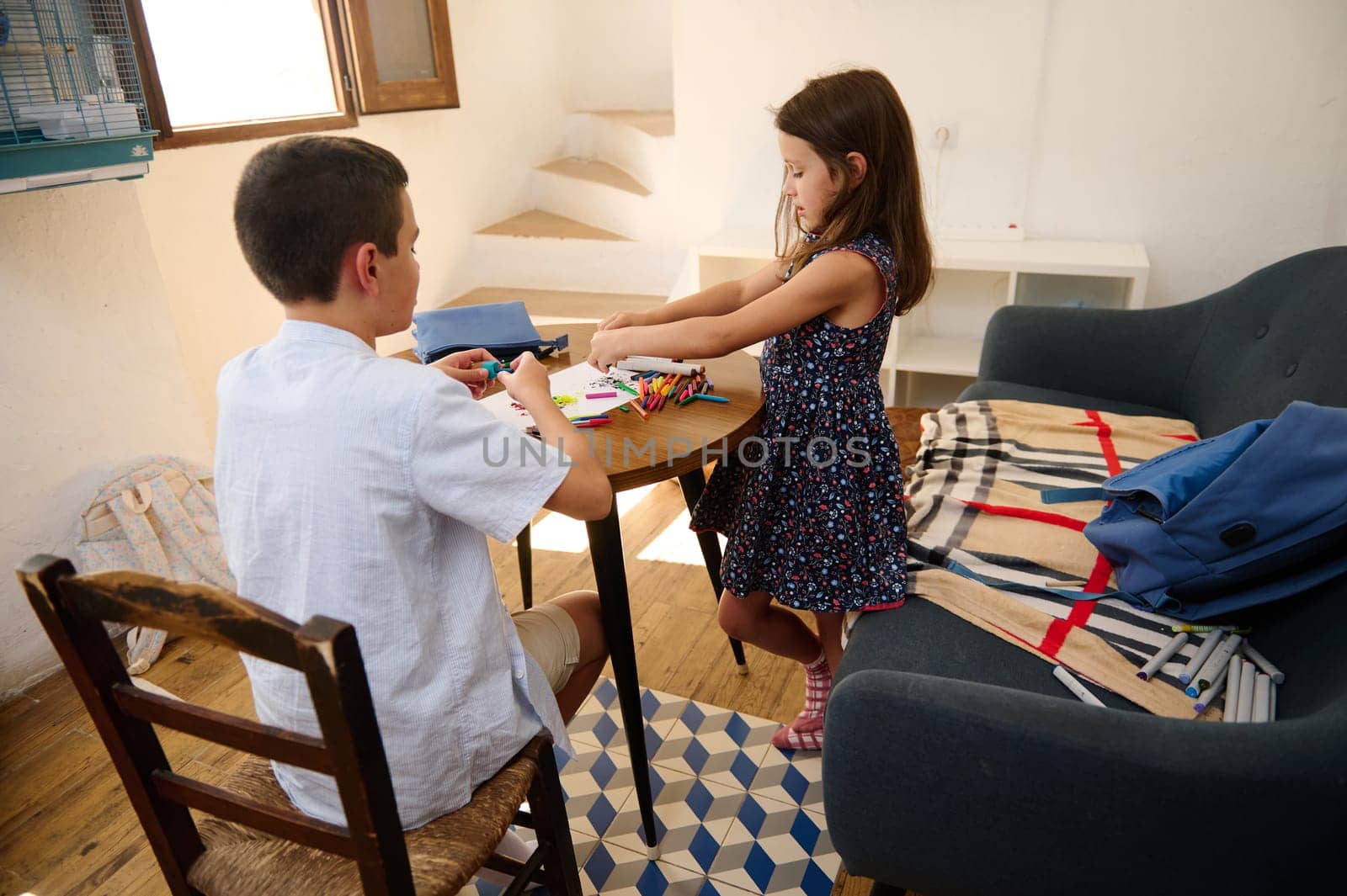 Two children enjoy a creative activity at a table in a cozy room, surrounded by artistic supplies.