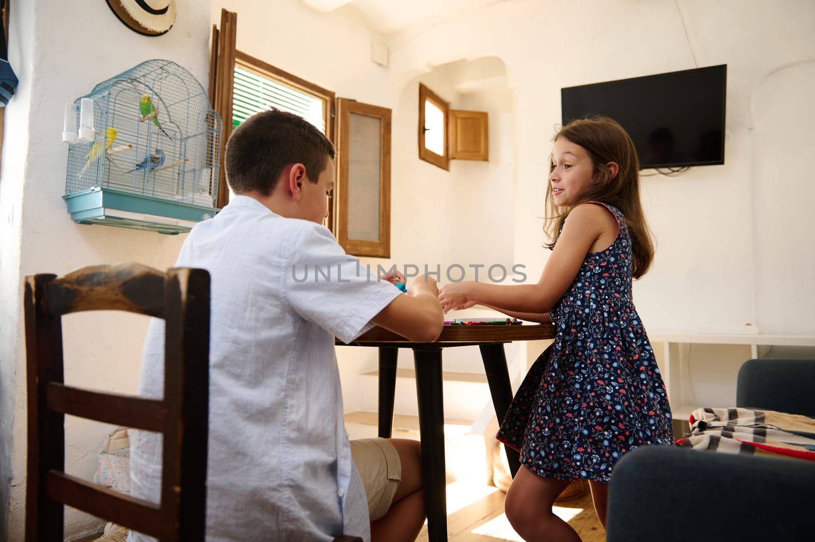 Two children engaging in a creative activity indoors, fostering interaction and youthful joy in a cozy, well-lit home setting.