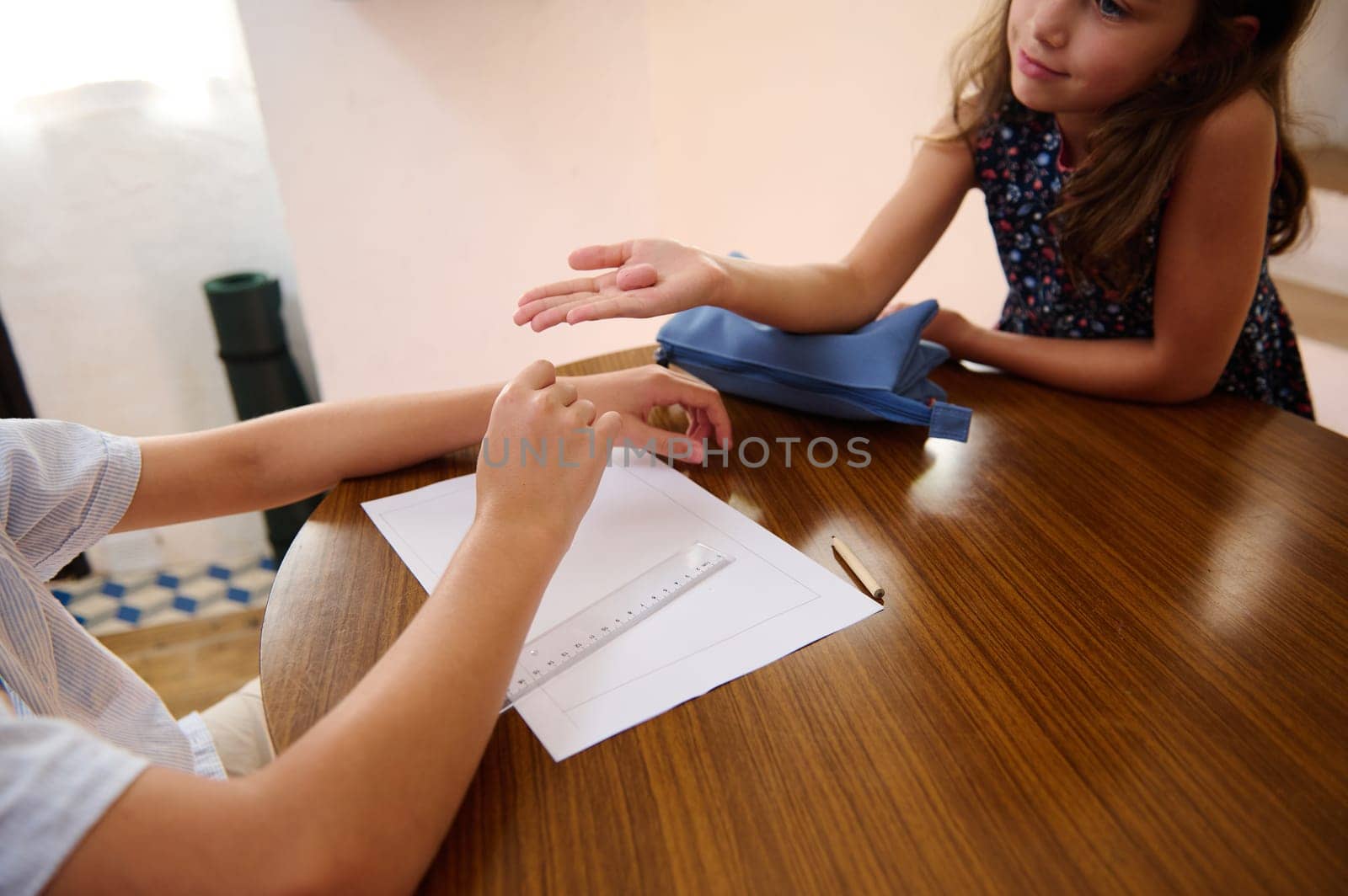 Two children sit at a table engaging attentively, exhibiting curiosity and communication.