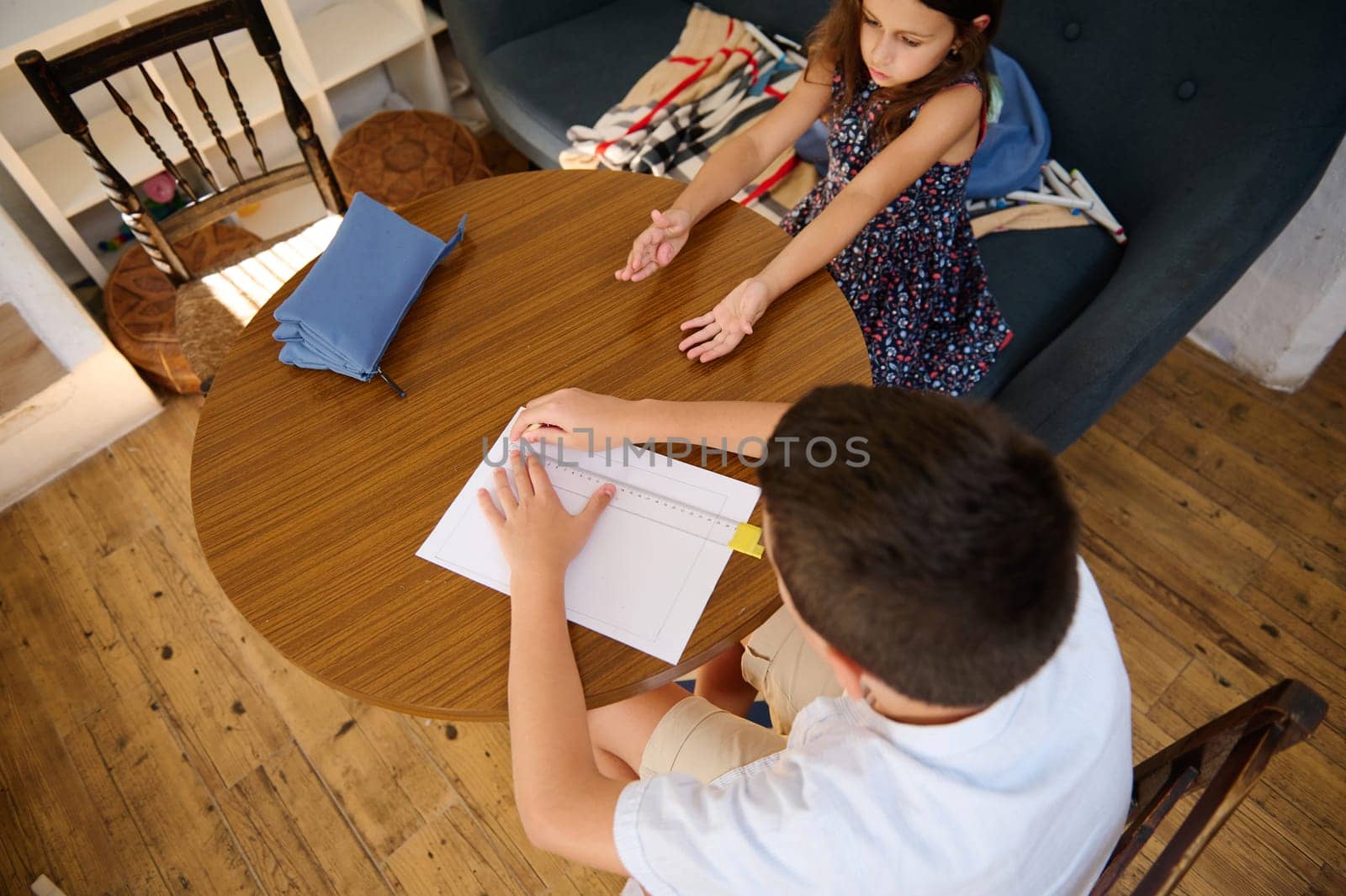 Two children studying together at a wooden table in a cozy interior setting, focusing on collaboration and education.