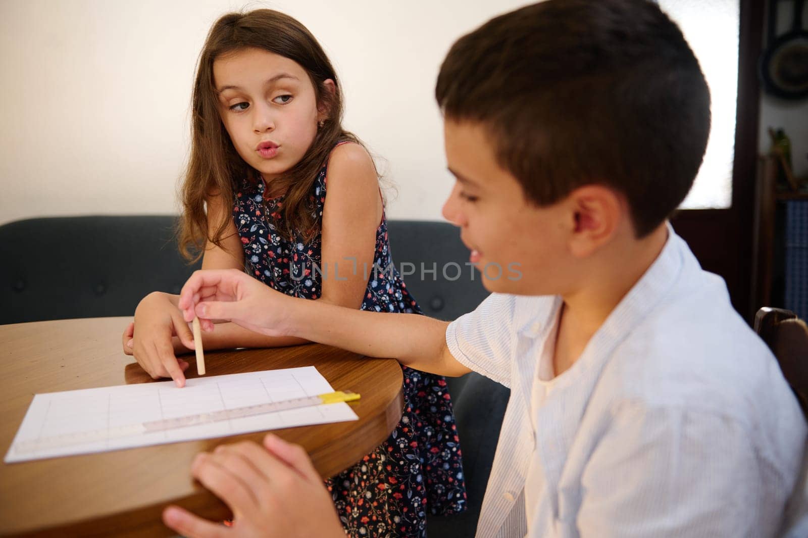 Two children working together on an assignment at a table, showcasing teamwork and education.