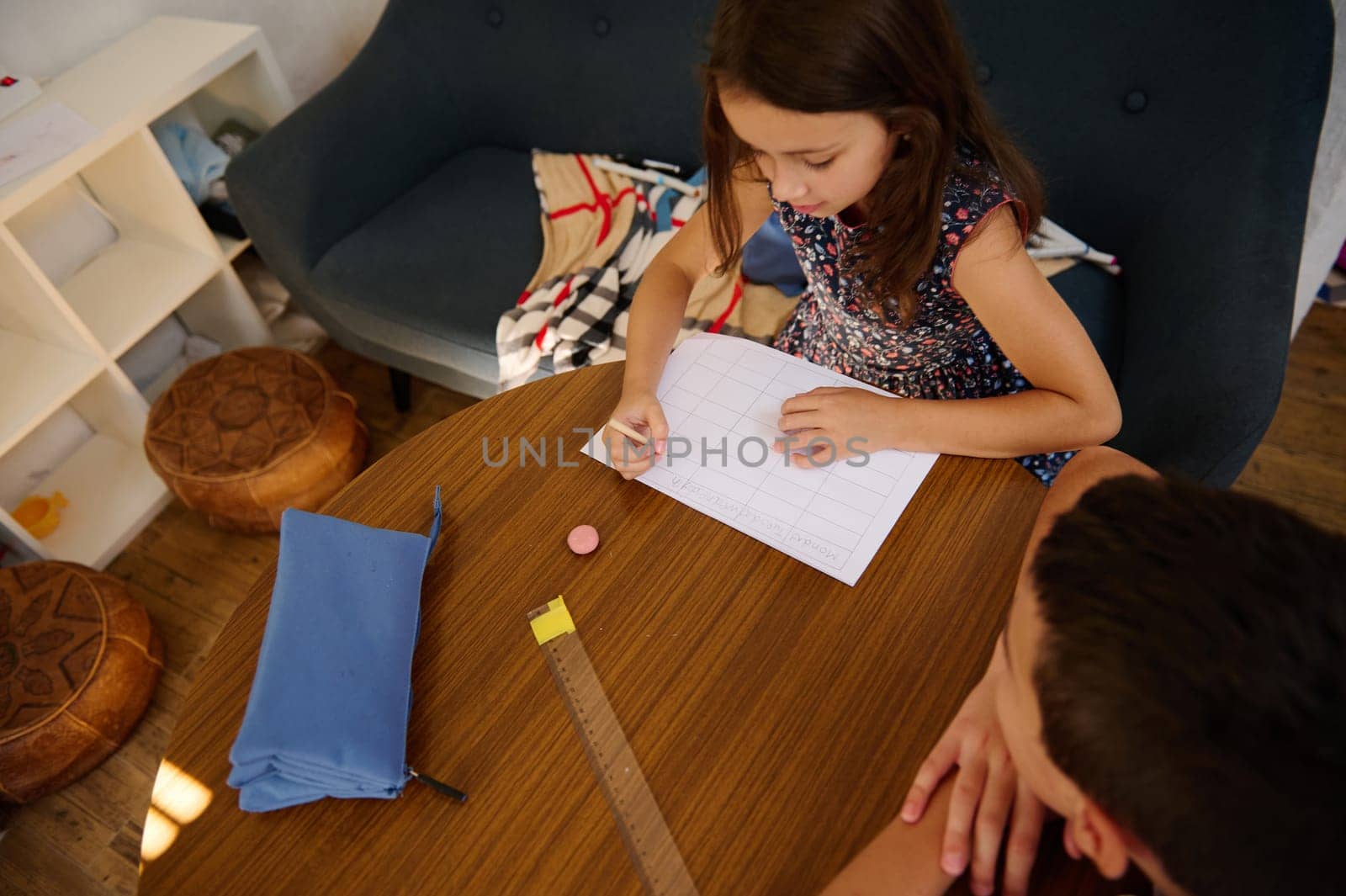 Two children studying and writing at a table indoors, showcasing education and learning in a comfortable and cozy home environment.