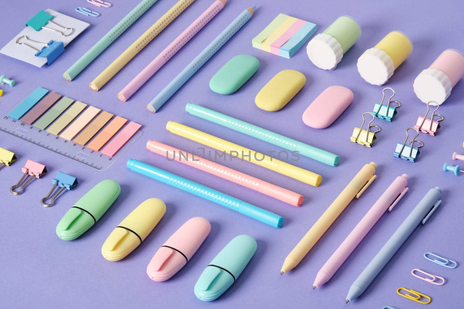 Stationery background with pastel-colored stationery neatly arranged on a light purple background.