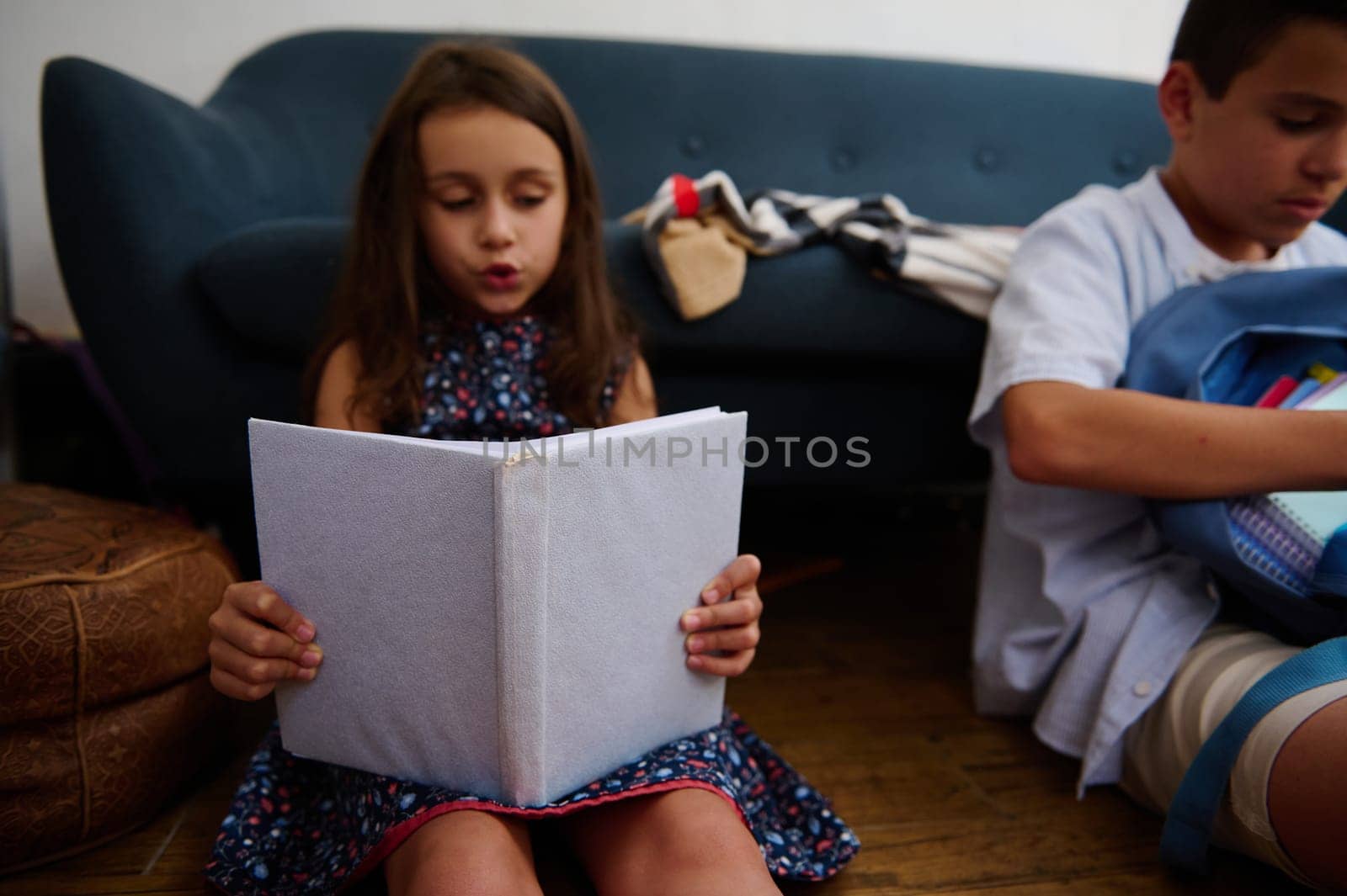 A young girl attentively reads a book while sitting indoors, fostering a love for learning and imagination.