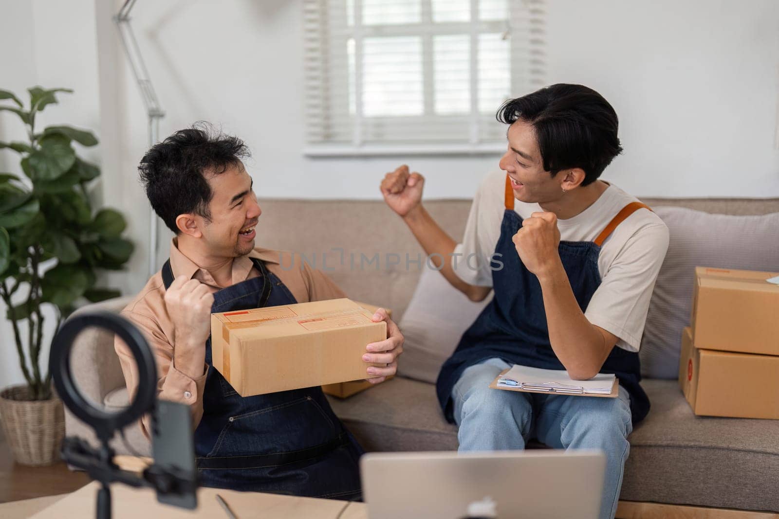 Two enthusiastic partners in a home office, celebrating and sharing excitement as they unbox products, showcasing their entrepreneurial spirit and teamwork.