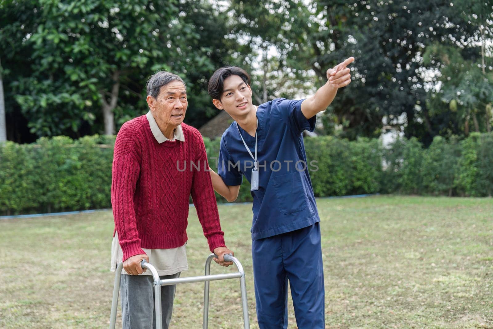 A young caregiver assists an elderly man with a walker, pointing at interesting sights in a vibrant garden, fostering connection and encouraging mobility.