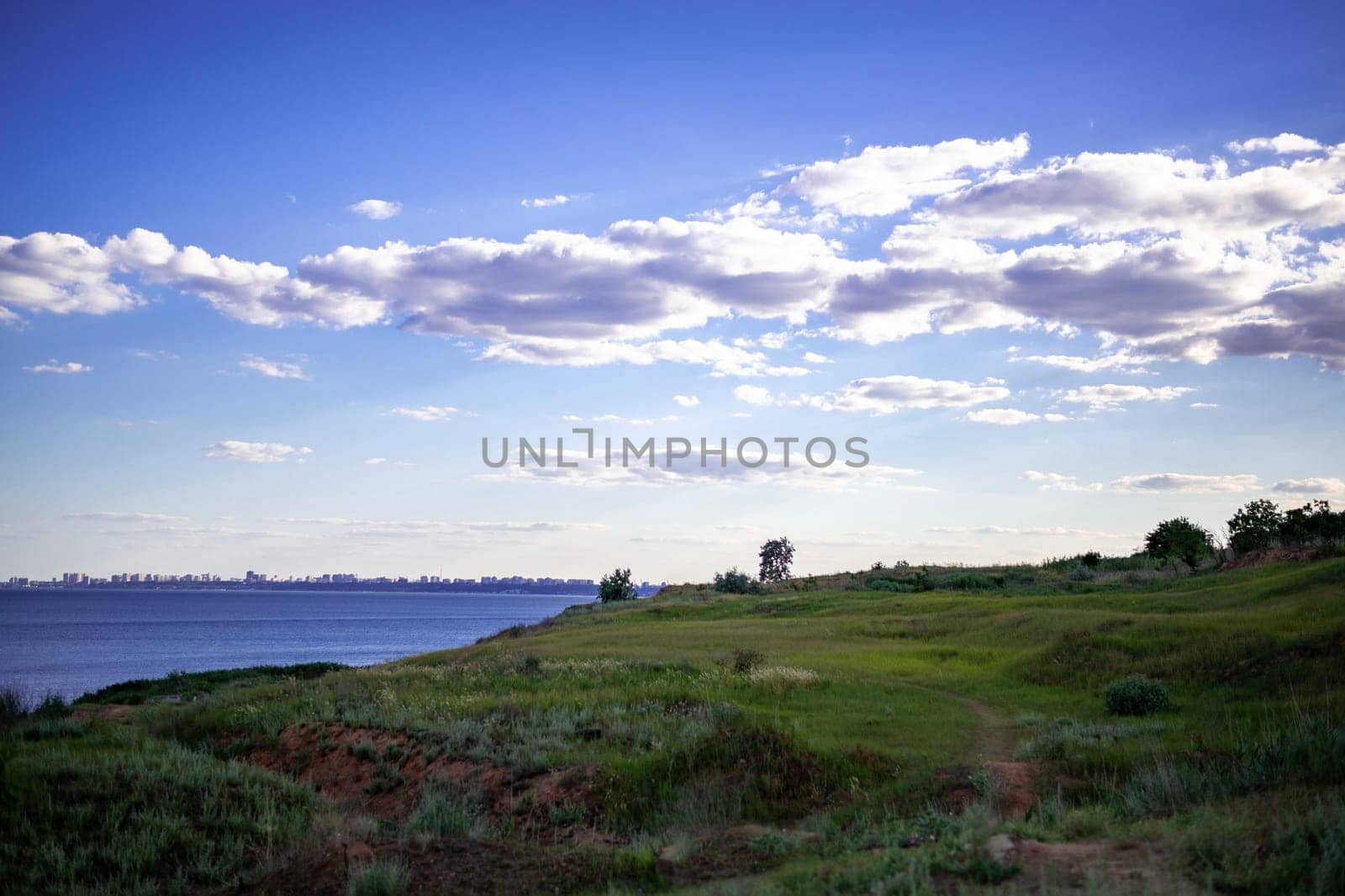 the path goes through a grassy landscape. the sea is on the horizon. the city is visible in the distance