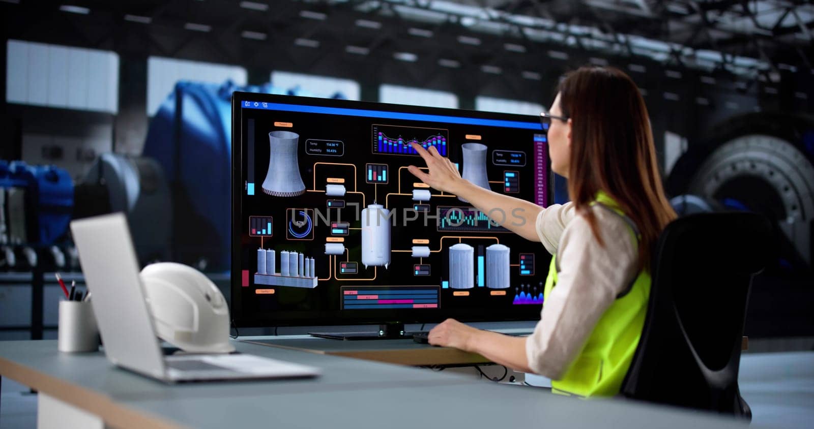 Young female engineer operates SCADA system at oil refinery power plant.