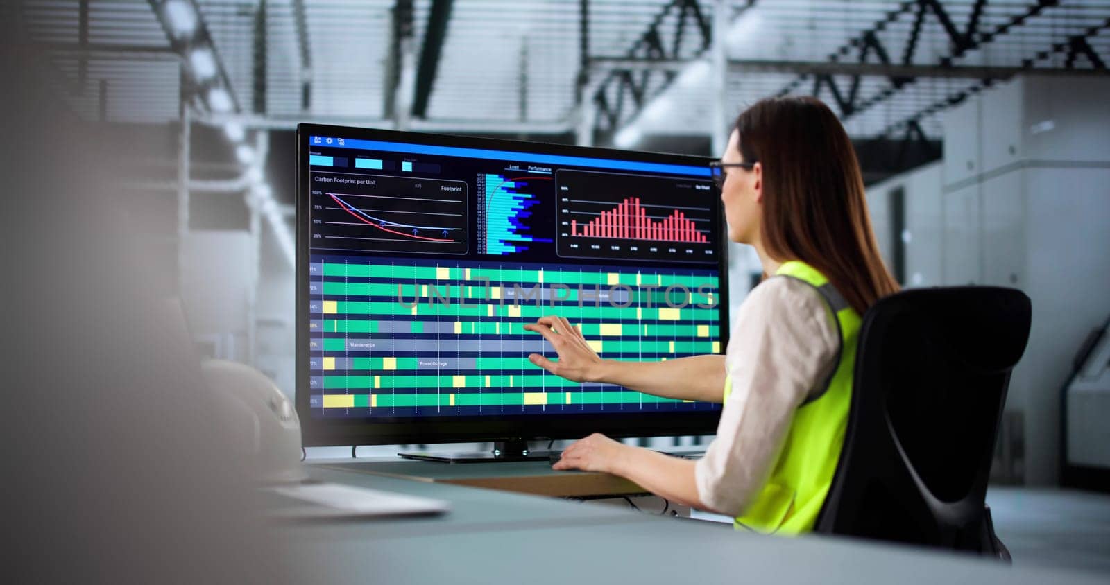Young engineer using computer to manage production line at factory.   Woman technician connecting energy efficient systems in advanced automated factory.