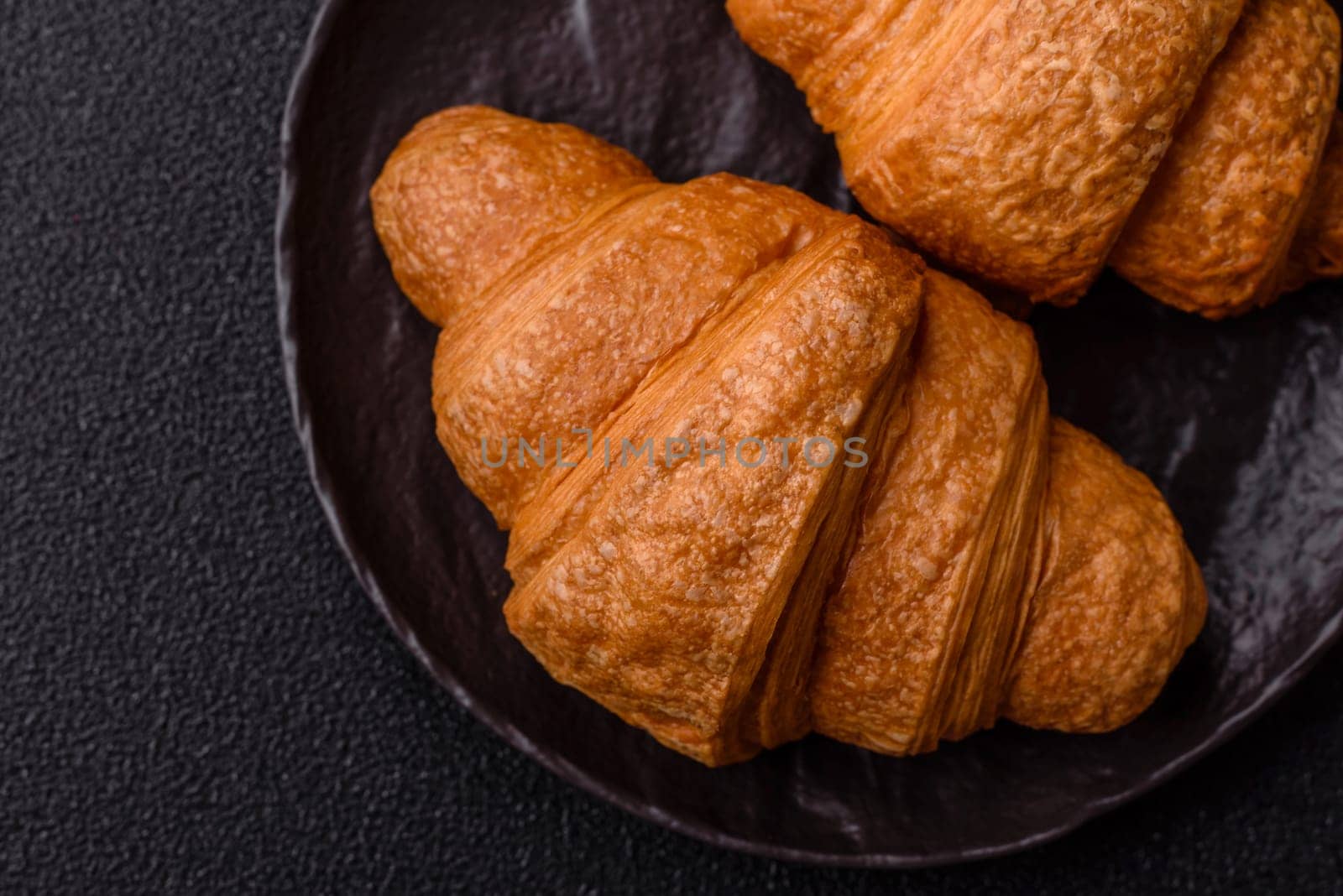 Sweet crispy croissants with chocolate filling on a dark concrete background