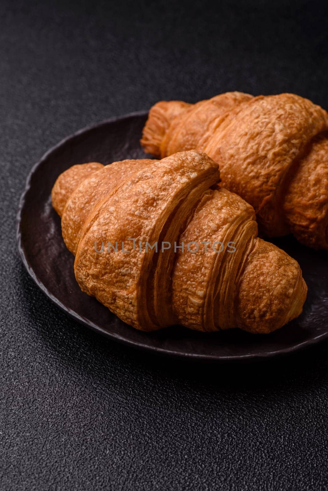 Sweet crispy croissants with chocolate filling on a dark concrete background