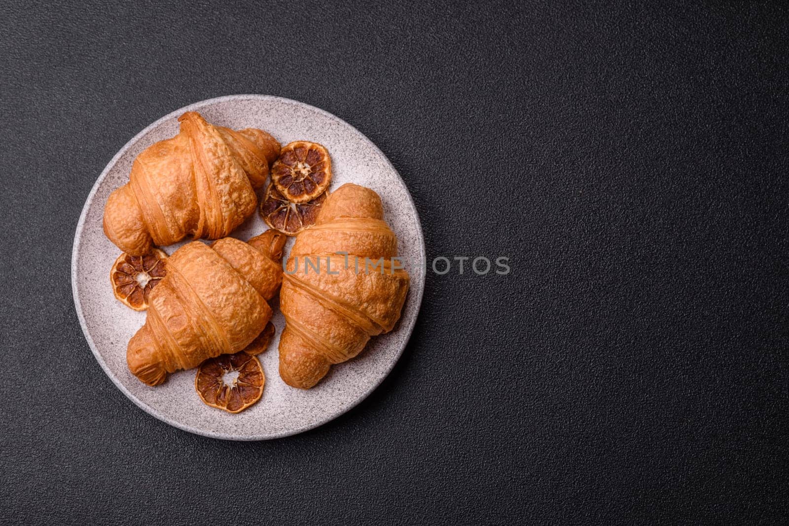 Sweet crispy croissants with chocolate filling on a dark concrete background