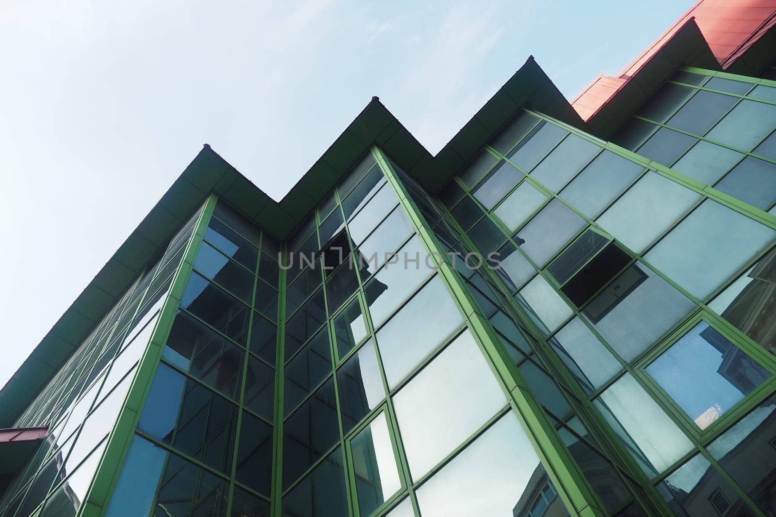 Unique building with angular design and green glass reflecting sunlight.