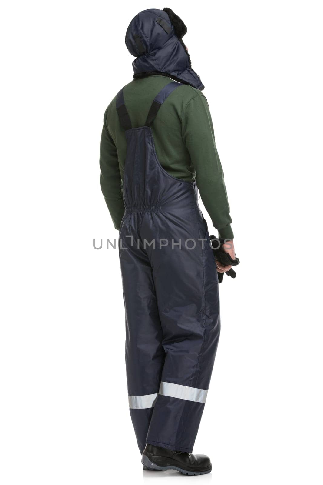 Man in blue work overalls and winter cap isolated full-length rearview
