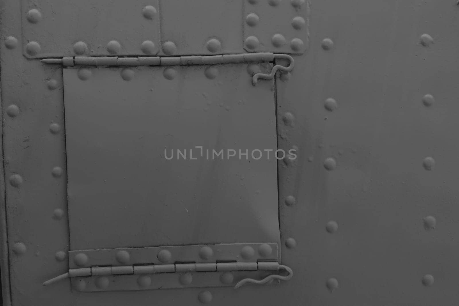Green metal background with rivets. Side of military equipment with a technical hatch.