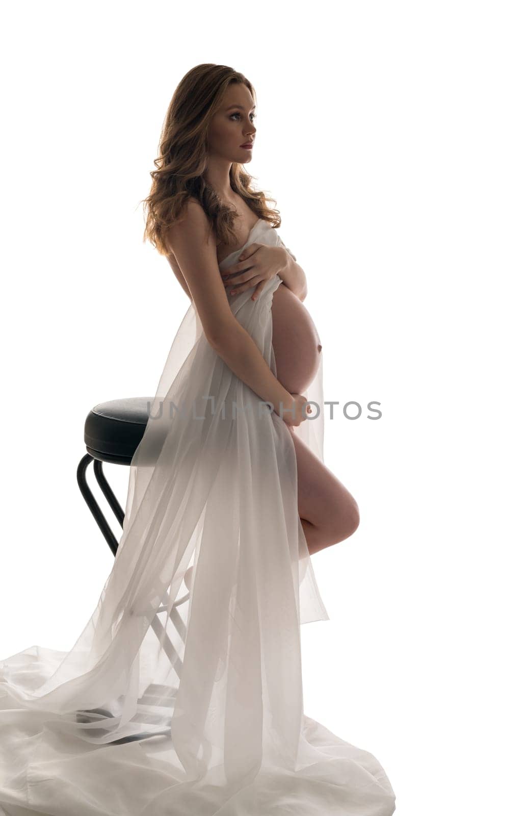 Pregnant girl with long locks sitting on bar stool profile isolated portrait