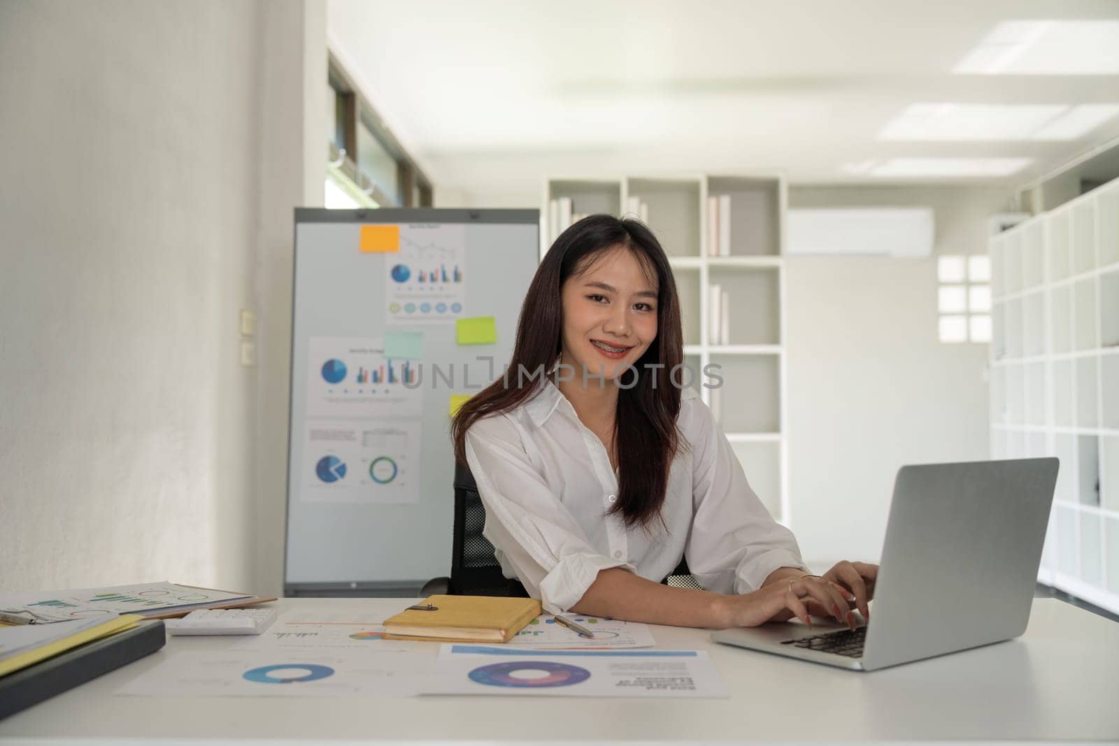 Portrait of beautiful young businesswoman asian sitting at office modern work station and typing on laptop.