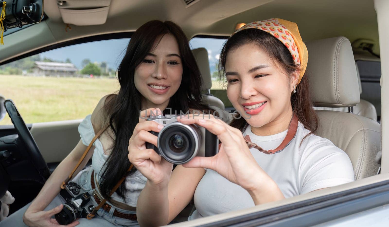 Cute Asian female friends enjoying taking photos with a camera together during a trip. and enjoy traveling on holidays by wichayada
