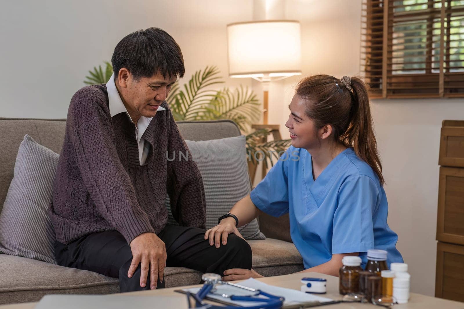 Caregivers assist elderly man with check-ups and physical therapy while he is recover at home. by wichayada