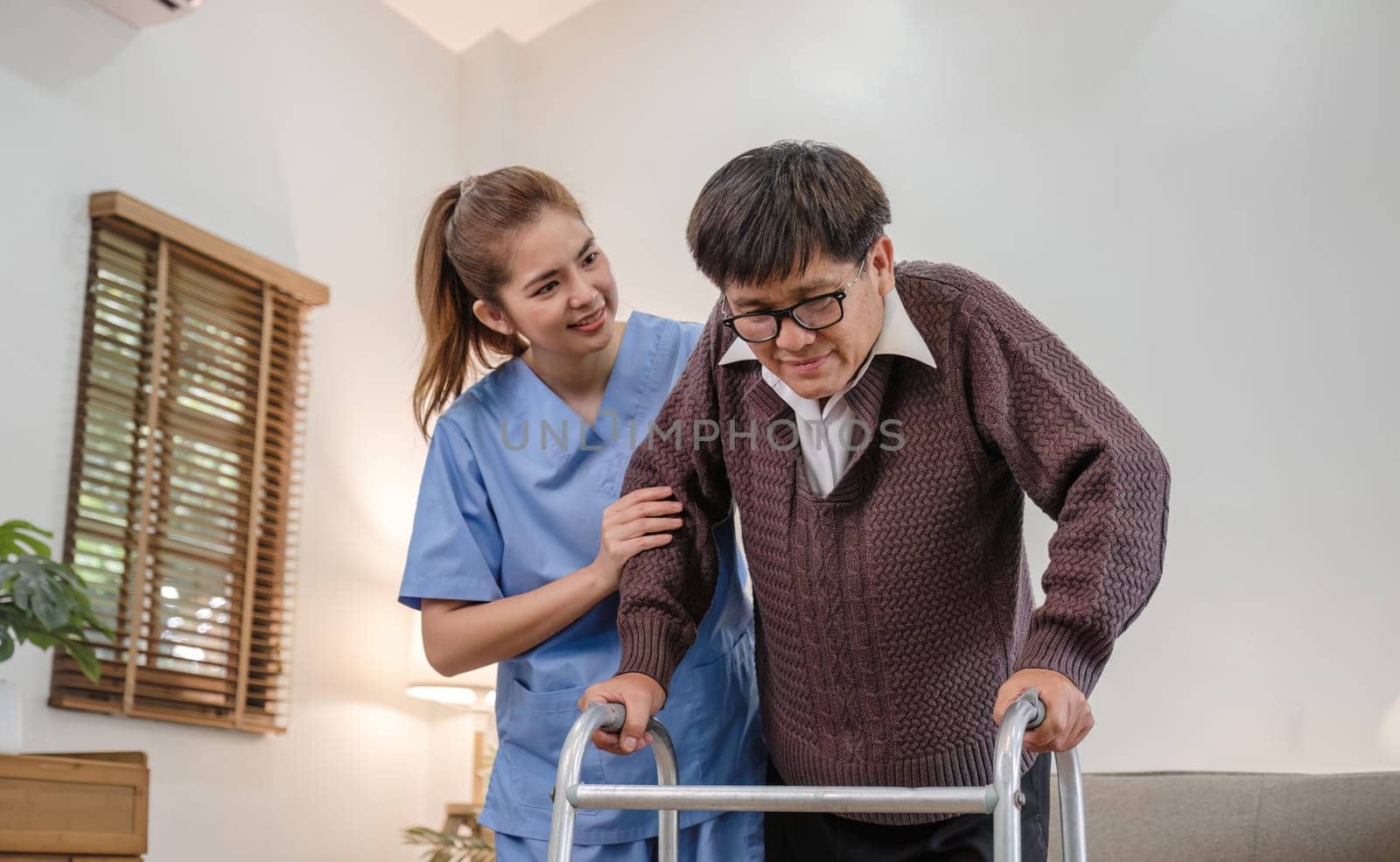 young asian female nurse care giver helping asian senior old man with mobility walker in living area of nursing home senior daycare center. Nurse take care elderly patient with cheerful concentrate.