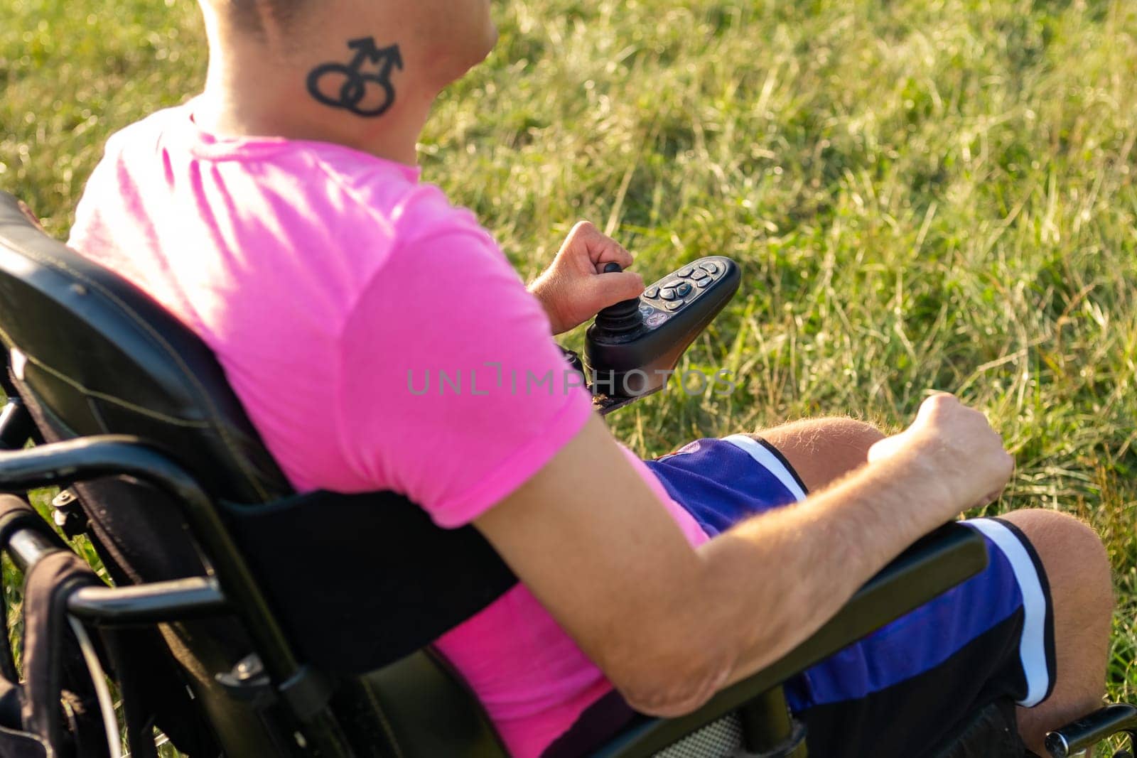 Disabled man with LGBT tattoo using joystick in electric wheelchair