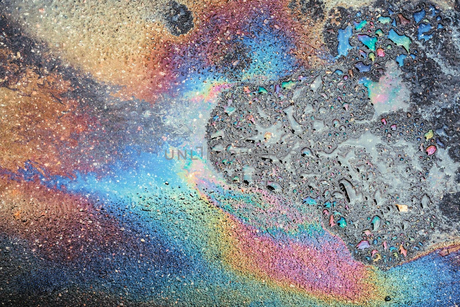 Colored oil stains close up, the color of the gasoline stain on the pavement road as a texture or background.