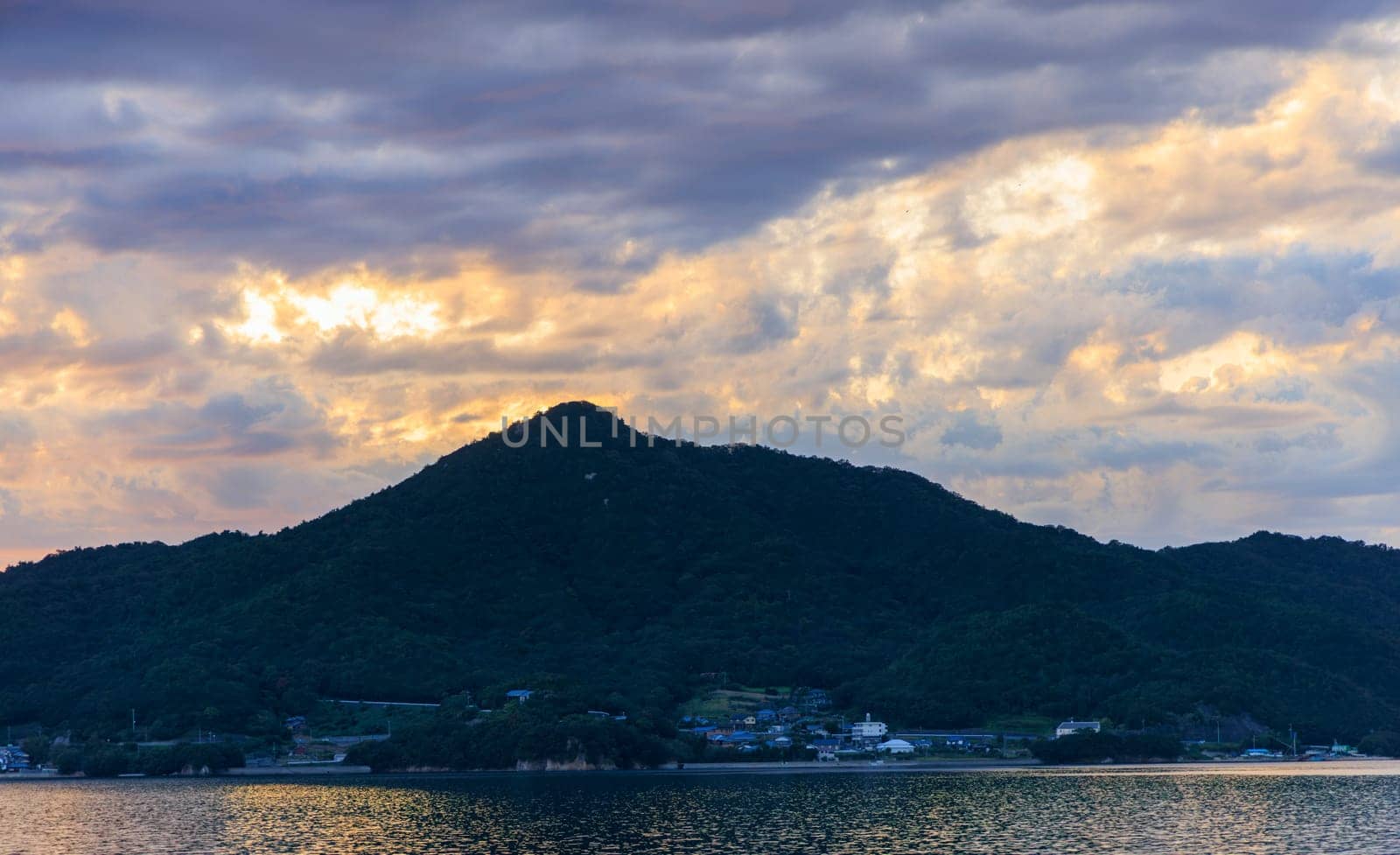 Dramatic sunset clouds over small coastal village and mountain. High quality photo
